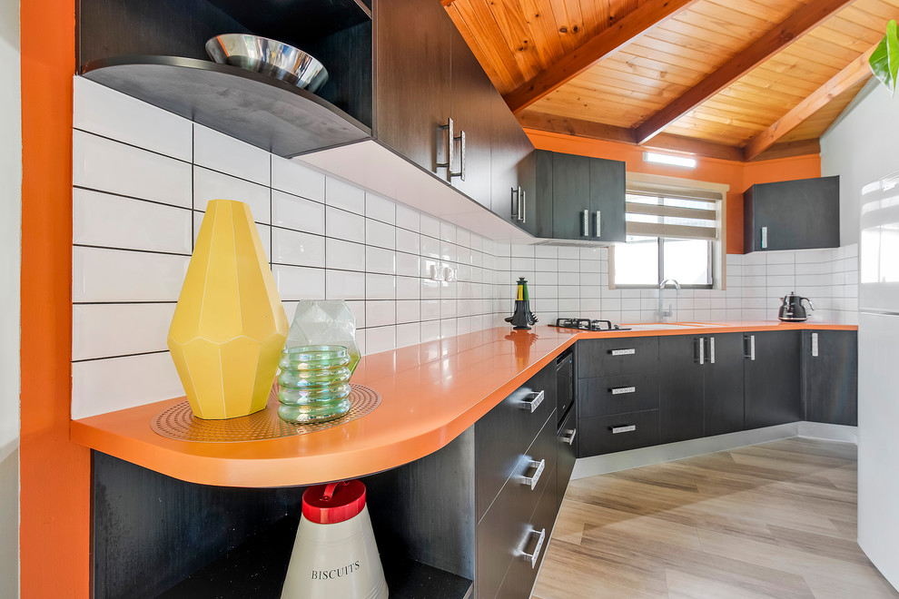 Свежая идея для дизайна: маленькая отдельная, прямая кухня в стиле модернизм с монолитной мойкой, столешницей из акрилового камня, желтым фартуком, фартуком из плитки кабанчик и оранжевой столешницей для на участке и в саду - отличное фото интерьера