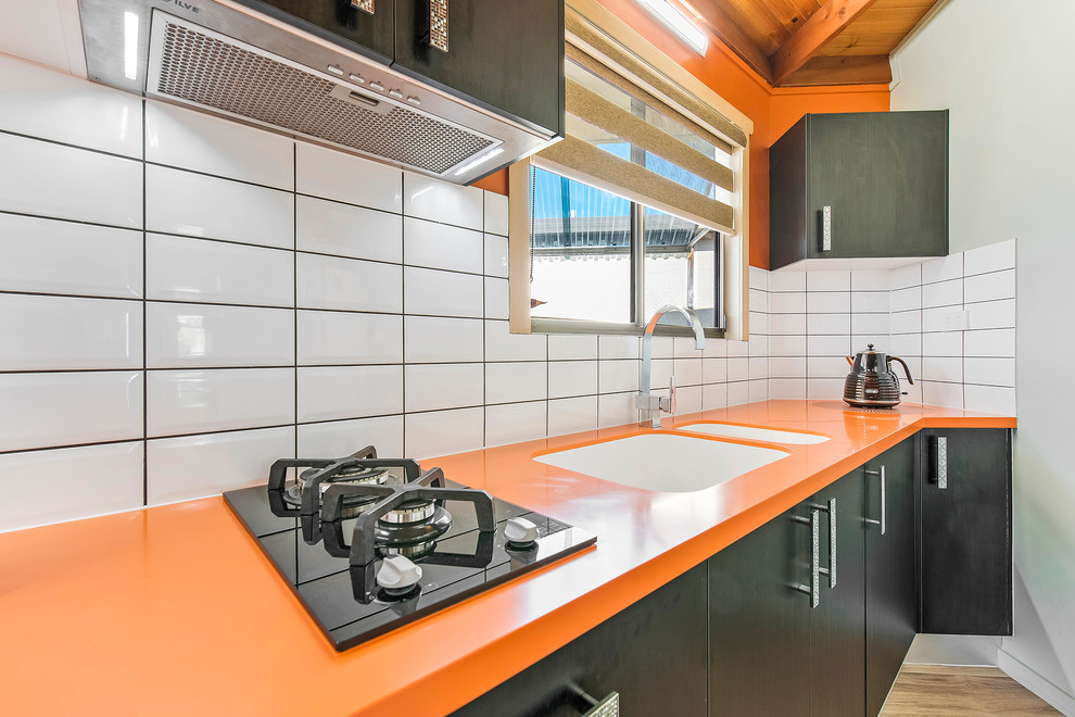 Foto de cocina lineal moderna pequeña cerrada con fregadero integrado, encimera de acrílico, salpicadero amarillo, salpicadero de azulejos tipo metro y encimeras naranjas