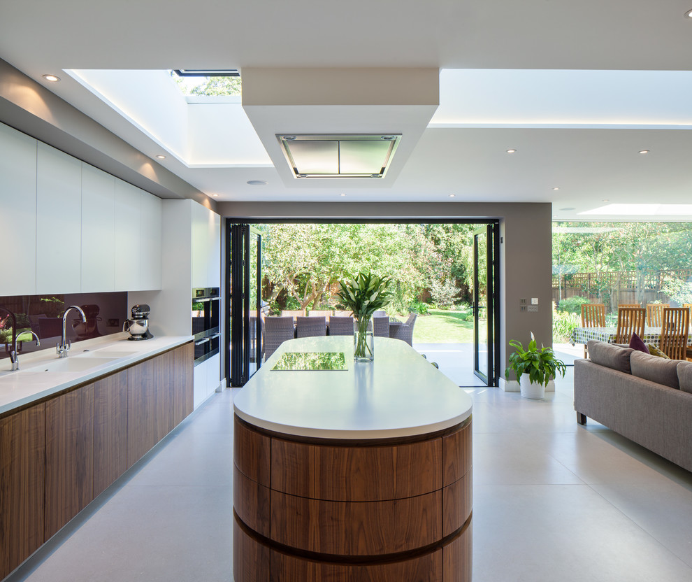 Photo of a contemporary galley open plan kitchen in London with flat-panel cabinets, dark wood cabinets, brown splashback, glass sheet splashback and an island.