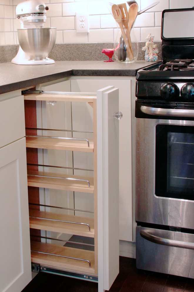 Exempel på ett avskilt, litet modernt l-kök, med en undermonterad diskho, skåp i shakerstil, vita skåp, granitbänkskiva, vitt stänkskydd, stänkskydd i keramik, rostfria vitvaror och mörkt trägolv