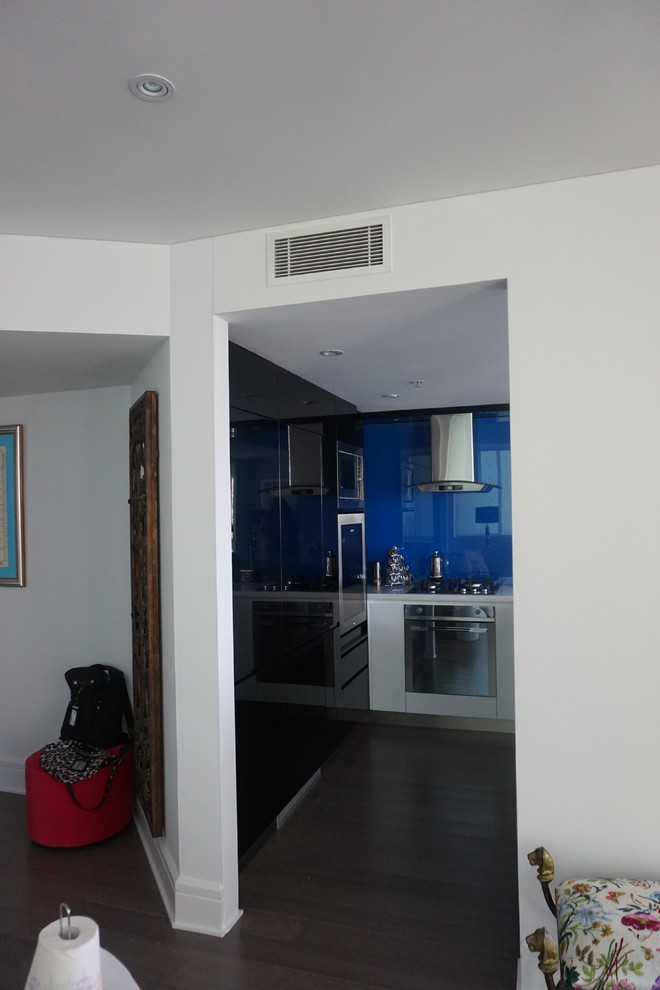 Kleine Moderne Wohnküche in U-Form mit Einbauwaschbecken, weißen Schränken, Quarzwerkstein-Arbeitsplatte, Küchenrückwand in Blau, Glasrückwand, Küchengeräten aus Edelstahl und Bambusparkett in Sydney