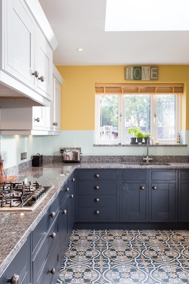 Bild på ett mellanstort vintage kök, med skåp i shakerstil, grå skåp, granitbänkskiva, grönt stänkskydd, glaspanel som stänkskydd, klinkergolv i porslin och flerfärgat golv