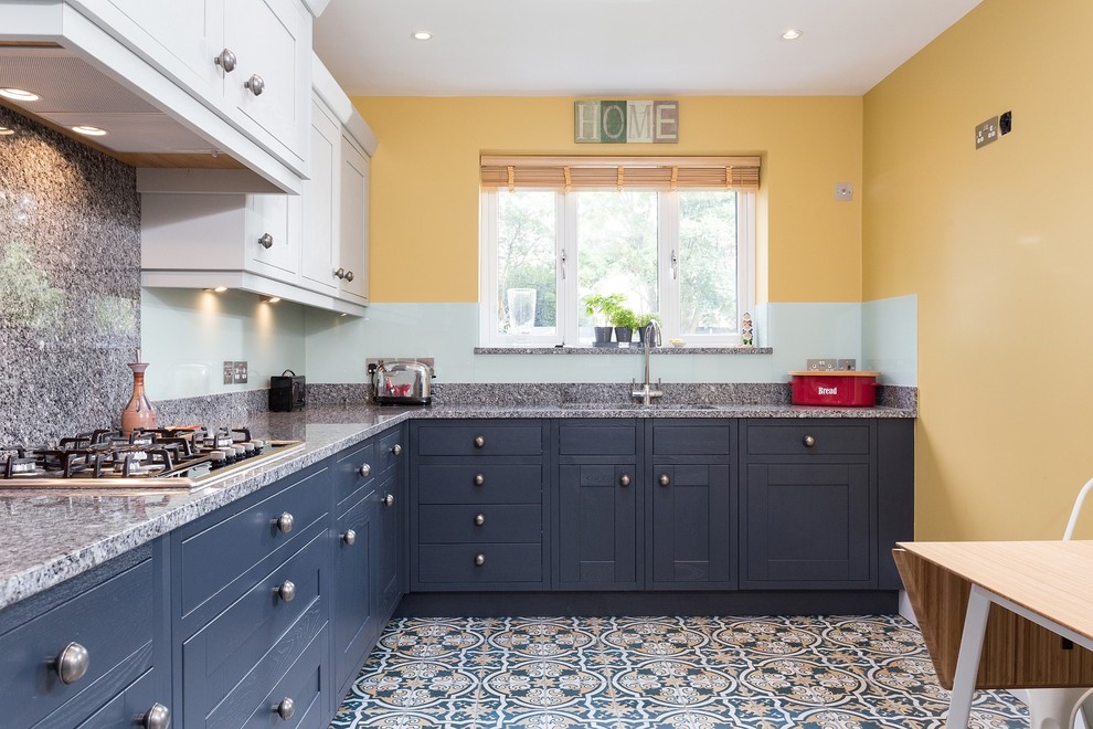 Photo of a medium sized classic l-shaped kitchen/diner in London with shaker cabinets, grey cabinets, granite worktops, green splashback, glass sheet splashback, porcelain flooring, no island and multi-coloured floors.