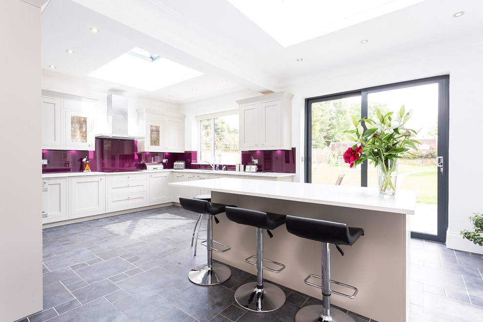 Große Küche in U-Form mit Schrankfronten im Shaker-Stil, weißen Schränken, Küchenrückwand in Rosa, Glasrückwand und Kücheninsel in London