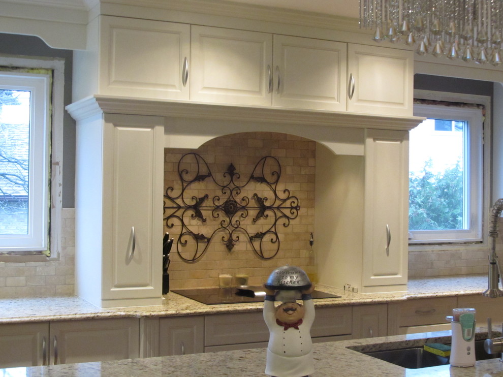 Foto på ett mellanstort funkis kök, med en undermonterad diskho, luckor med upphöjd panel, vita skåp, granitbänkskiva, beige stänkskydd, stänkskydd i stenkakel, rostfria vitvaror, ljust trägolv och en köksö