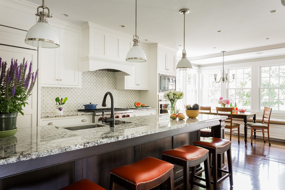 Klassische Wohnküche mit Doppelwaschbecken, Schrankfronten im Shaker-Stil, weißen Schränken, bunter Rückwand, Küchengeräten aus Edelstahl, braunem Holzboden und Kücheninsel in Boston