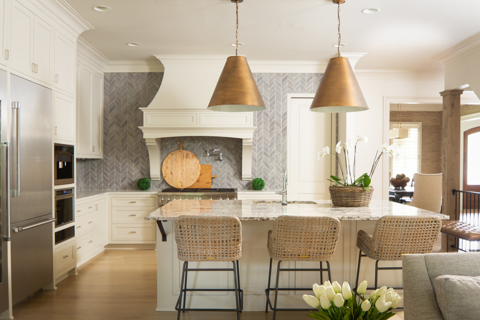 Inspiration for a farmhouse l-shaped medium tone wood floor and brown floor kitchen remodel in Atlanta with an undermount sink, recessed-panel cabinets, white cabinets, gray backsplash, mosaic tile backsplash, stainless steel appliances, an island and beige countertops