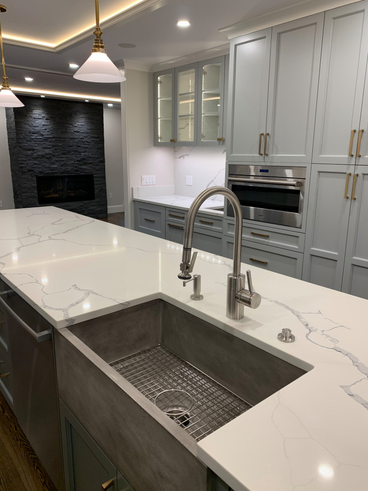Idee per una grande cucina tradizionale chiusa con lavello stile country, ante con bugna sagomata, ante grigie, top in quarzite, paraspruzzi bianco, paraspruzzi in lastra di pietra, elettrodomestici in acciaio inossidabile, parquet scuro, pavimento marrone e top bianco