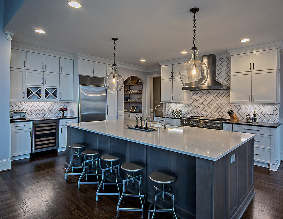 Large transitional l-shaped medium tone wood floor and brown floor open concept kitchen photo in Atlanta with a farmhouse sink, shaker cabinets, white cabinets, quartzite countertops, white backsplash, subway tile backsplash, stainless steel appliances and an island