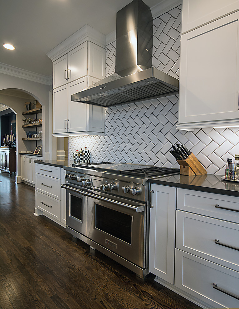 Large transitional l-shaped medium tone wood floor and brown floor open concept kitchen photo in Atlanta with a farmhouse sink, shaker cabinets, white cabinets, quartzite countertops, white backsplash, subway tile backsplash, stainless steel appliances and an island
