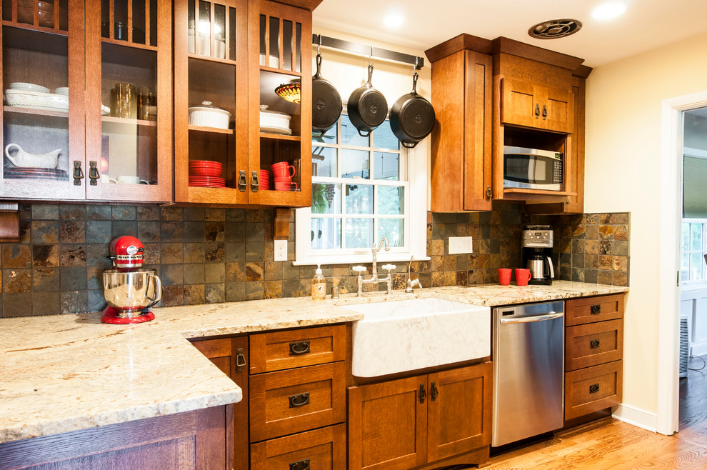 Photo of a small classic galley kitchen/diner in Milwaukee with a belfast sink, shaker cabinets, medium wood cabinets, granite worktops, green splashback, stone tiled splashback, stainless steel appliances, medium hardwood flooring and a breakfast bar.