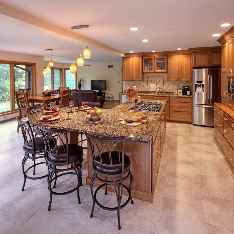 This is an example of a large classic l-shaped open plan kitchen in Milwaukee with a submerged sink, recessed-panel cabinets, medium wood cabinets, granite worktops, beige splashback, ceramic splashback, stainless steel appliances, ceramic flooring, an island, beige floors and brown worktops.