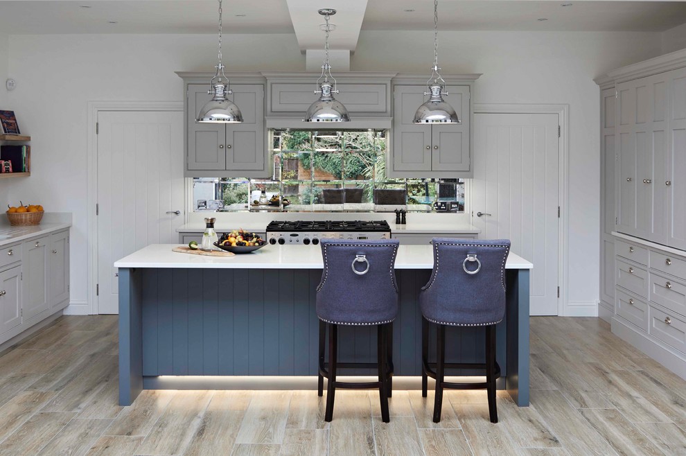 Klassische Küche in U-Form mit Schrankfronten im Shaker-Stil, blauen Schränken, Rückwand aus Spiegelfliesen, Kücheninsel und beigem Boden in London