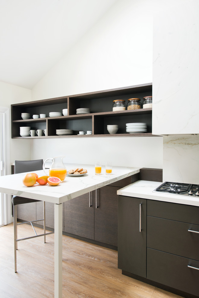 Imagen de cocina lineal contemporánea con armarios con paneles lisos, suelo de madera clara, península, encimeras blancas y con blanco y negro