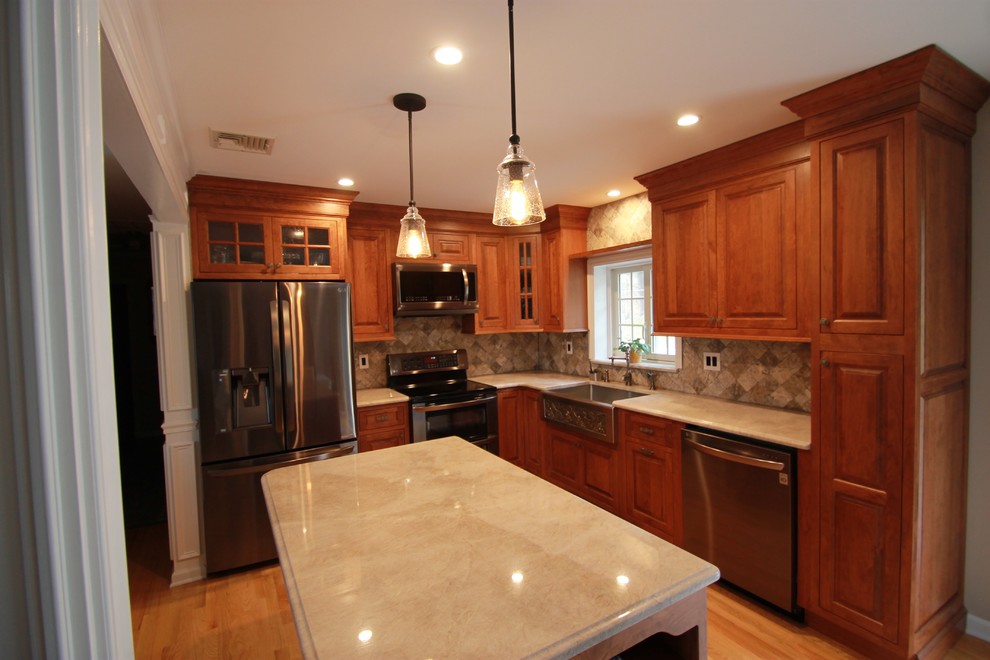 Example of a mid-sized classic l-shaped light wood floor eat-in kitchen design in New York with a farmhouse sink, raised-panel cabinets, medium tone wood cabinets, granite countertops, gray backsplash, stone tile backsplash, stainless steel appliances and an island