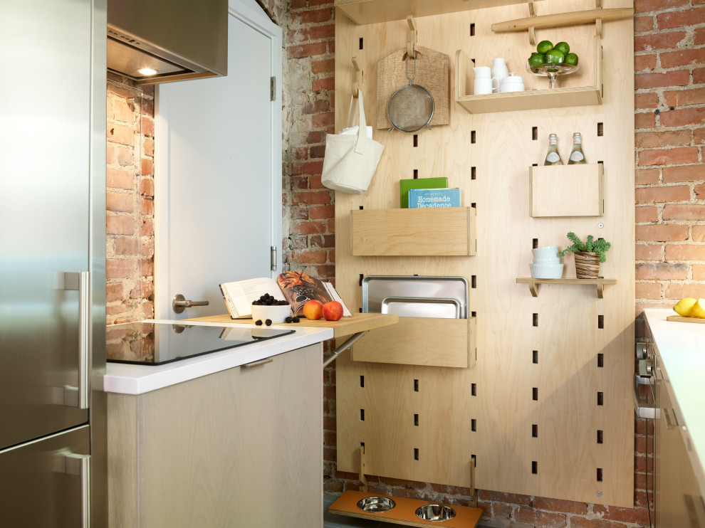Cette image montre une petite cuisine parallèle design en bois clair fermée avec un placard à porte plane et aucun îlot.