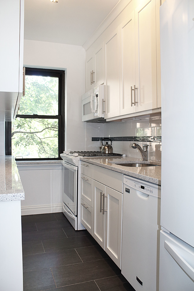 Example of a small trendy galley porcelain tile enclosed kitchen design in New York with an undermount sink, shaker cabinets, white cabinets, quartzite countertops, white backsplash, ceramic backsplash and white appliances