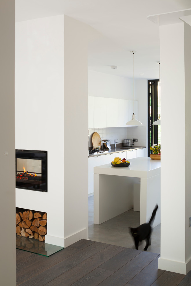 Стильный дизайн: прямая кухня-гостиная среднего размера в современном стиле с плоскими фасадами, белыми фасадами, бетонным полом и островом - последний тренд
