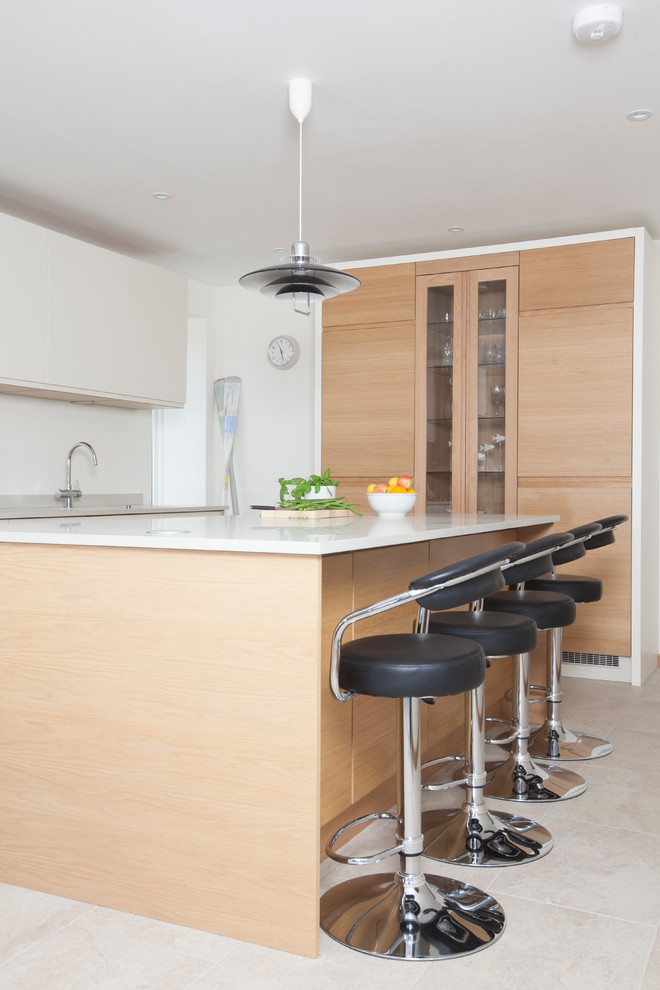 Eat-in kitchen - mid-sized contemporary l-shaped ceramic tile eat-in kitchen idea in Cardiff with a drop-in sink, flat-panel cabinets, white cabinets, solid surface countertops, glass tile backsplash, stainless steel appliances and an island