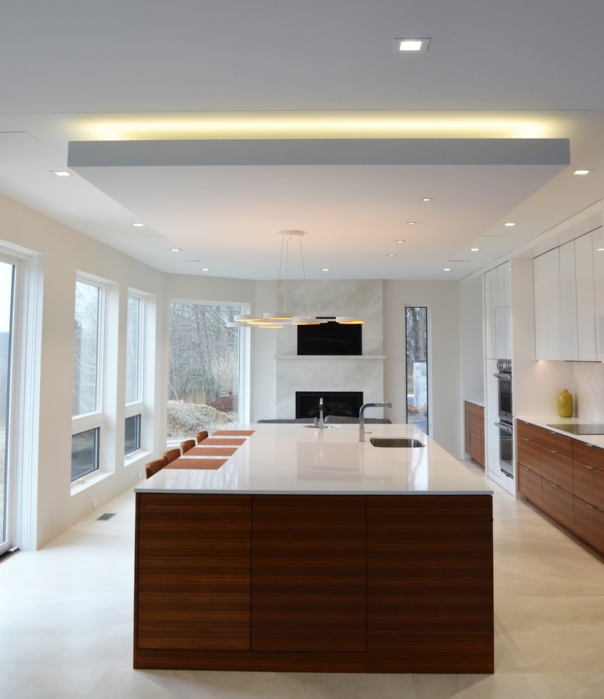 Design ideas for an expansive contemporary galley open plan kitchen in Other with a submerged sink, flat-panel cabinets, medium wood cabinets, glass worktops, beige splashback, porcelain splashback, stainless steel appliances, porcelain flooring, an island, beige floors and white worktops.