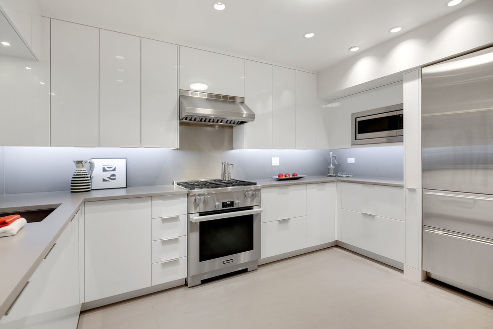 Modern inredning av ett mellanstort, avskilt grå grått u-kök, med släta luckor, vita skåp, grått stänkskydd, grått golv, en undermonterad diskho och rostfria vitvaror