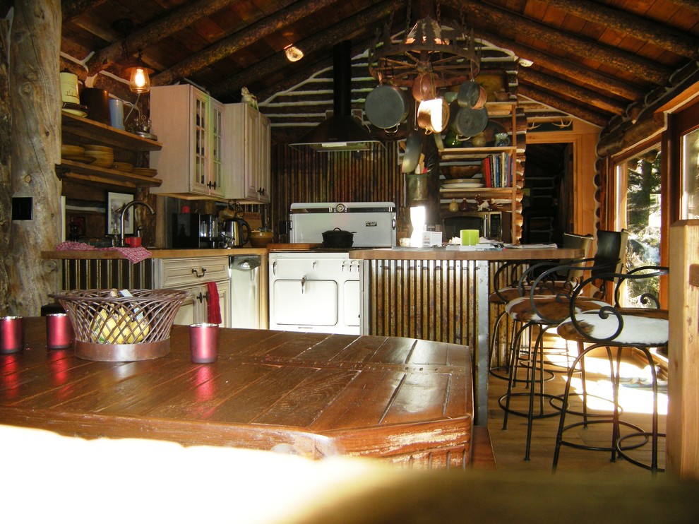 Bild på ett mellanstort rustikt kök, med luckor med upphöjd panel, skåp i slitet trä, träbänkskiva, vita vitvaror, en halv köksö, en nedsänkt diskho och mellanmörkt trägolv