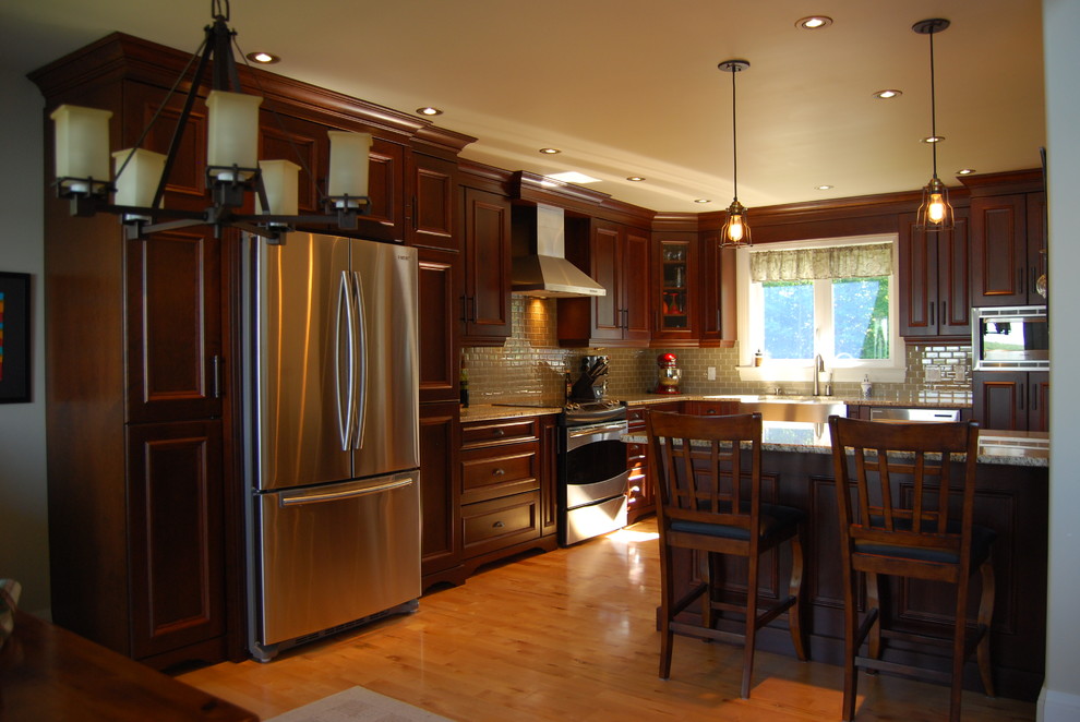 Example of a classic l-shaped light wood floor eat-in kitchen design in Ottawa with a farmhouse sink, beaded inset cabinets, medium tone wood cabinets, granite countertops, green backsplash, glass tile backsplash, stainless steel appliances and an island