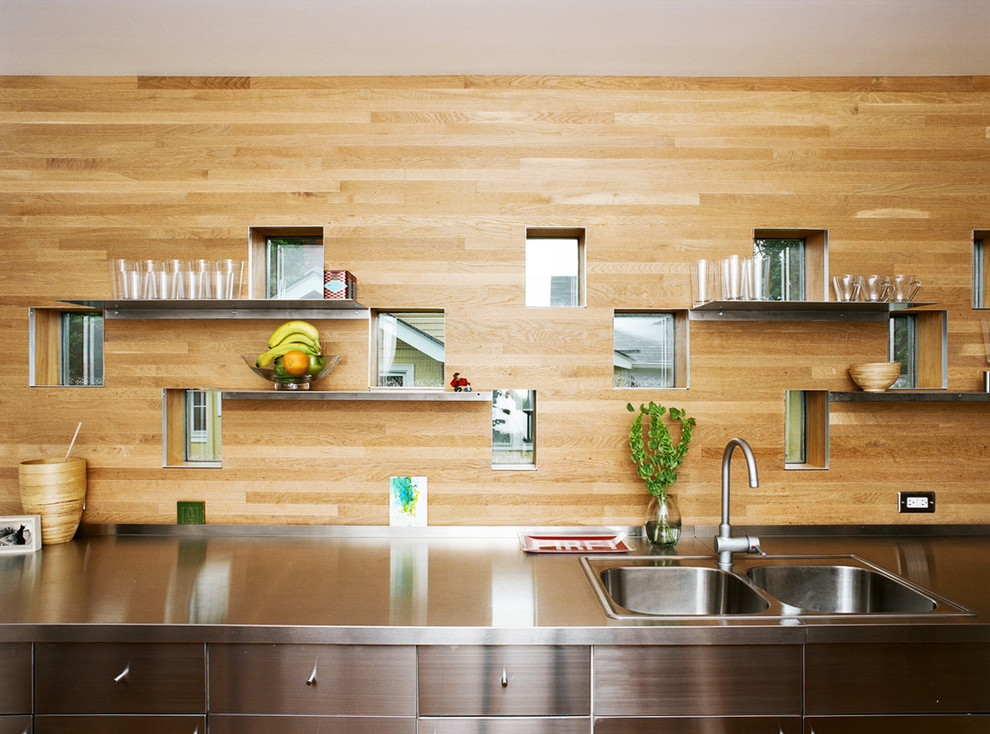 На фото: кухня в современном стиле с накладной мойкой, фасадами из нержавеющей стали и столешницей из нержавеющей стали с