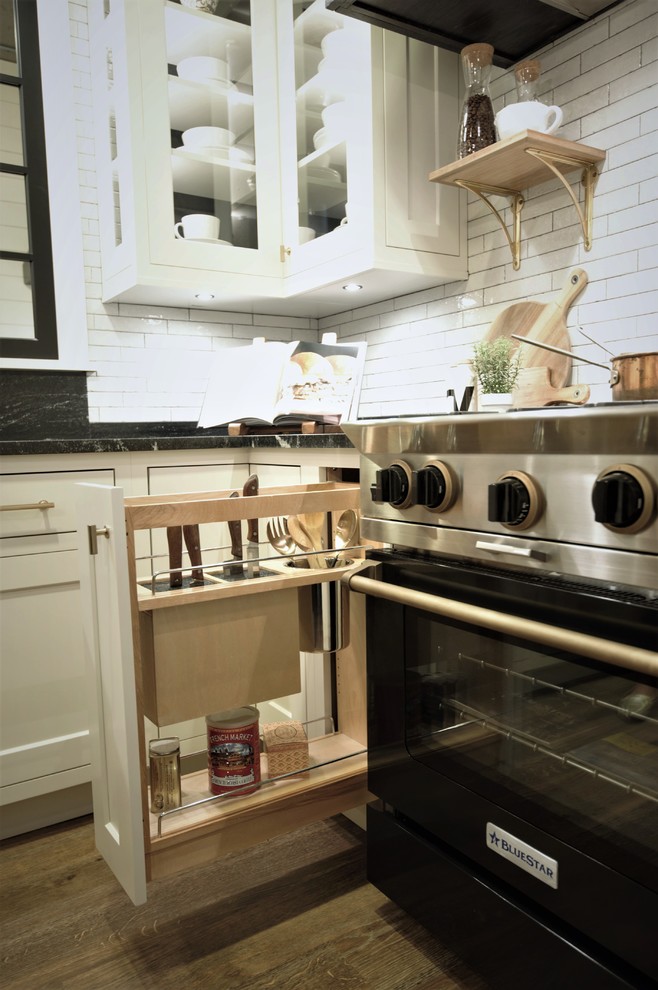 Modelo de cocina de estilo de casa de campo con puertas de armario blancas, encimera de granito, salpicadero blanco, suelo vinílico y una isla