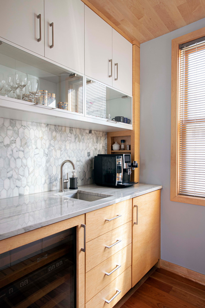 Diseño de cocina moderna con fregadero bajoencimera, puertas de armario de madera clara, salpicadero verde, suelo marrón y encimeras grises
