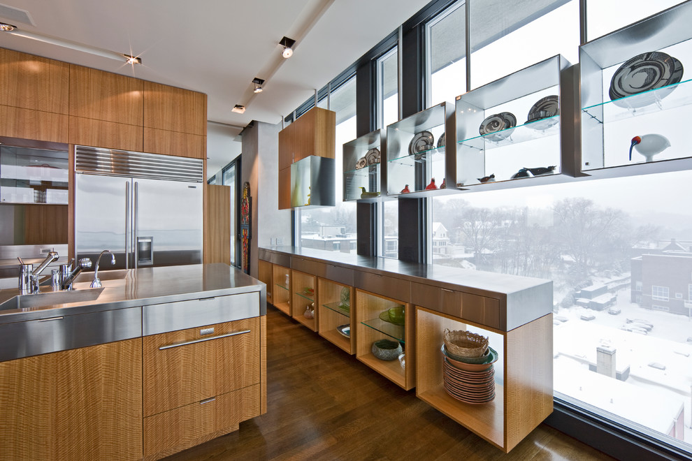 Moderne Küche mit integriertem Waschbecken, hellbraunen Holzschränken, Edelstahl-Arbeitsplatte, Küchengeräten aus Edelstahl und braunem Holzboden in Minneapolis
