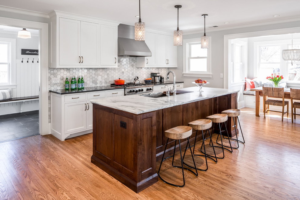 Diseño de cocina comedor tradicional con salpicadero de azulejos de piedra, electrodomésticos de acero inoxidable, suelo de madera en tonos medios, una isla, armarios estilo shaker, puertas de armario blancas y salpicadero multicolor