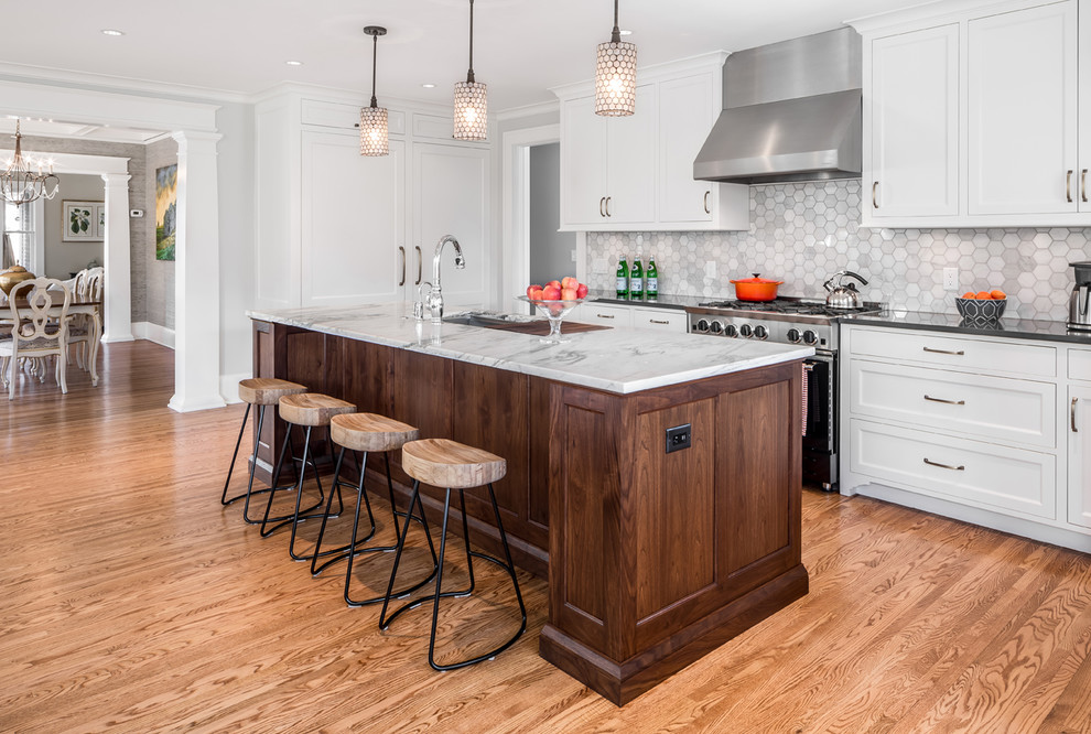 Design ideas for a classic l-shaped open plan kitchen in Minneapolis with flat-panel cabinets, grey splashback, stone tiled splashback, stainless steel appliances, medium hardwood flooring and an island.