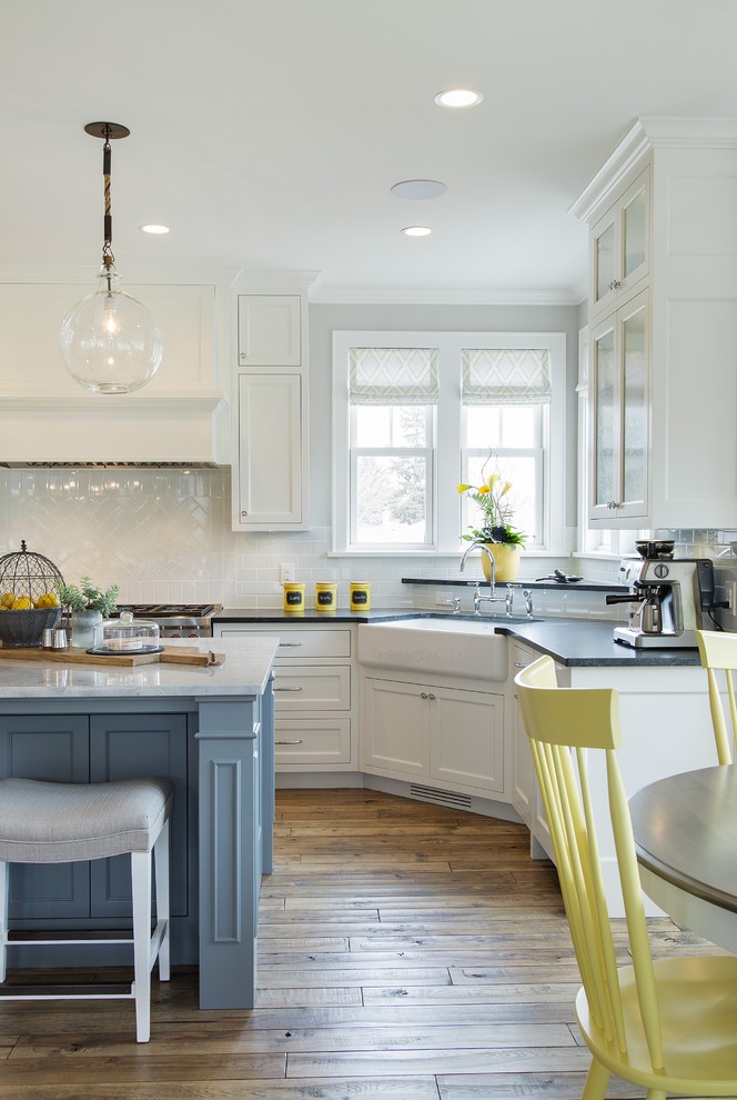 Eat-in kitchen - large farmhouse l-shaped medium tone wood floor eat-in kitchen idea in Minneapolis with a farmhouse sink, recessed-panel cabinets, white cabinets, marble countertops, white backsplash, ceramic backsplash, paneled appliances and an island