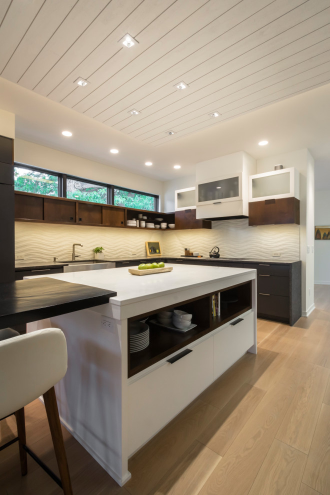 Large contemporary u-shaped kitchen in Minneapolis with a belfast sink, flat-panel cabinets, medium wood cabinets, beige splashback, an island, beige floors and white worktops.