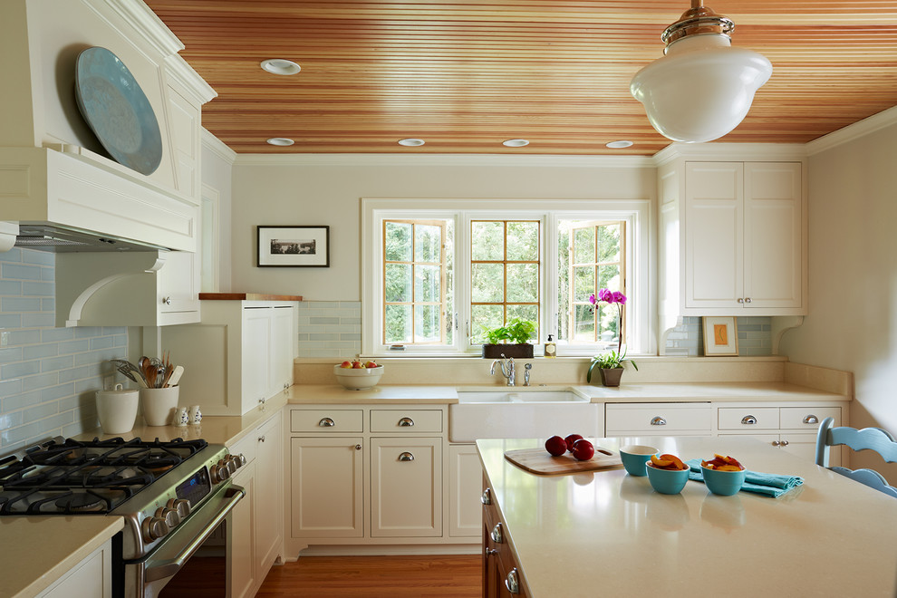 Exempel på ett mellanstort lantligt kök, med en rustik diskho, luckor med infälld panel, vita skåp, blått stänkskydd, stänkskydd i keramik, rostfria vitvaror, bänkskiva i kvarts, ljust trägolv och en köksö