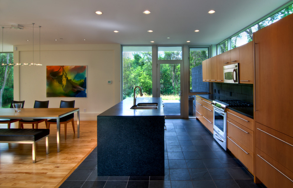 Example of a minimalist galley black floor eat-in kitchen design in Minneapolis with a double-bowl sink, flat-panel cabinets, medium tone wood cabinets, black backsplash and paneled appliances
