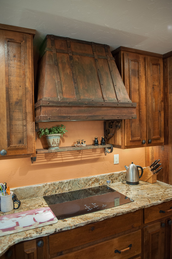 Foto di una cucina rustica con lavello sottopiano, ante con bugna sagomata, ante in legno scuro, top in granito, paraspruzzi beige e elettrodomestici in acciaio inossidabile