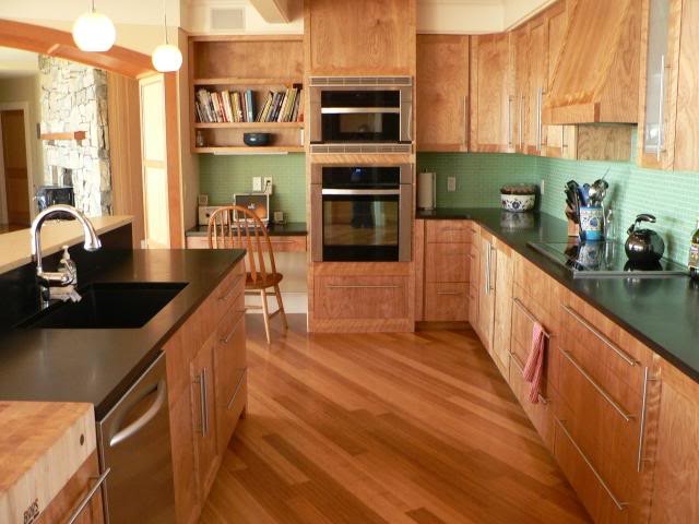Стильный дизайн: угловая кухня-гостиная среднего размера в стиле кантри с светлыми деревянными фасадами, зеленым фартуком, фартуком из стеклянной плитки, техникой из нержавеющей стали, паркетным полом среднего тона и островом - последний тренд