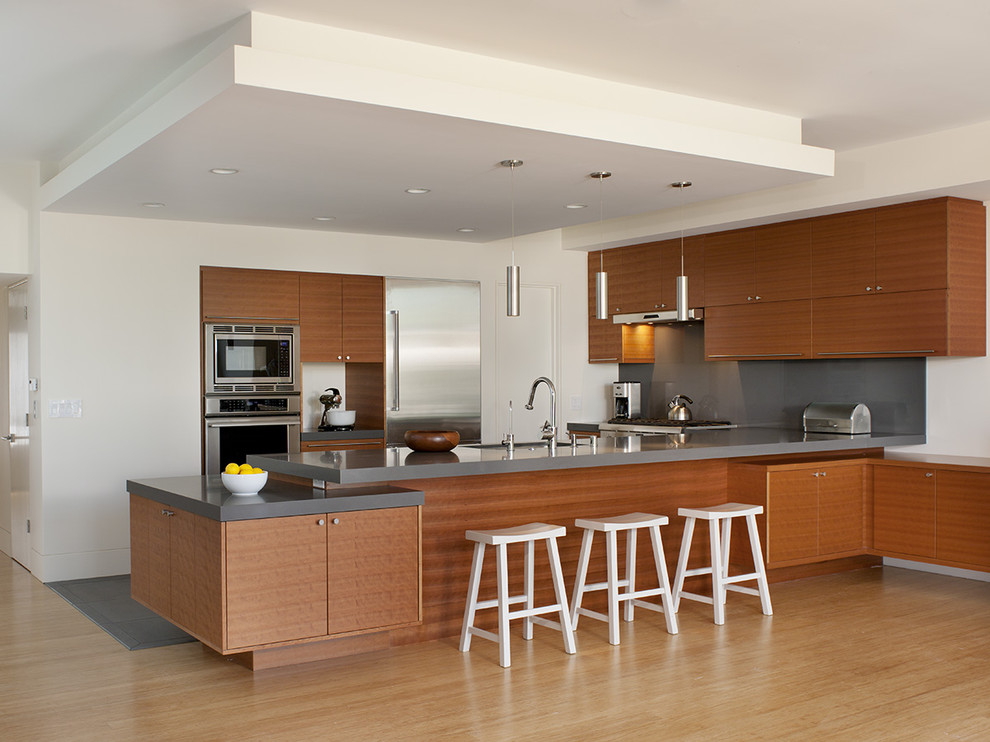 Идея дизайна: п-образная кухня в стиле модернизм с техникой из нержавеющей стали, плоскими фасадами и фасадами цвета дерева среднего тона