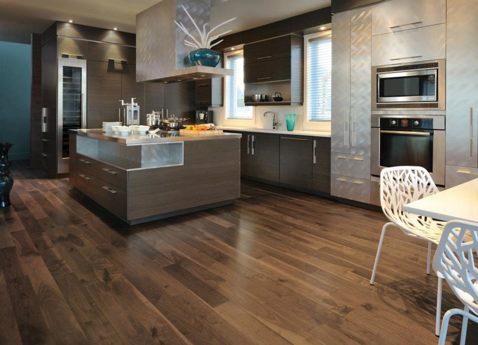 Example of a large minimalist l-shaped dark wood floor eat-in kitchen design in New York with an undermount sink, flat-panel cabinets, dark wood cabinets, stainless steel countertops, white backsplash, glass sheet backsplash, stainless steel appliances and an island
