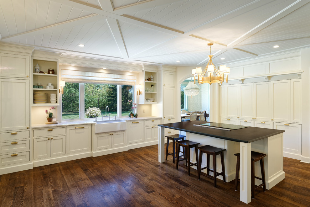 Design ideas for a classic kitchen in Cincinnati with a belfast sink, shaker cabinets, white cabinets, integrated appliances, medium hardwood flooring, an island and multicoloured worktops.