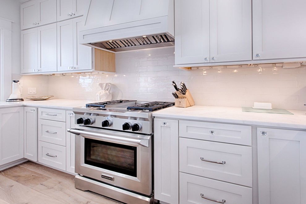 Inspiration for a large coastal u-shaped eat-in kitchen remodel with shaker cabinets, white cabinets, quartz countertops, white backsplash, subway tile backsplash, stainless steel appliances and an island