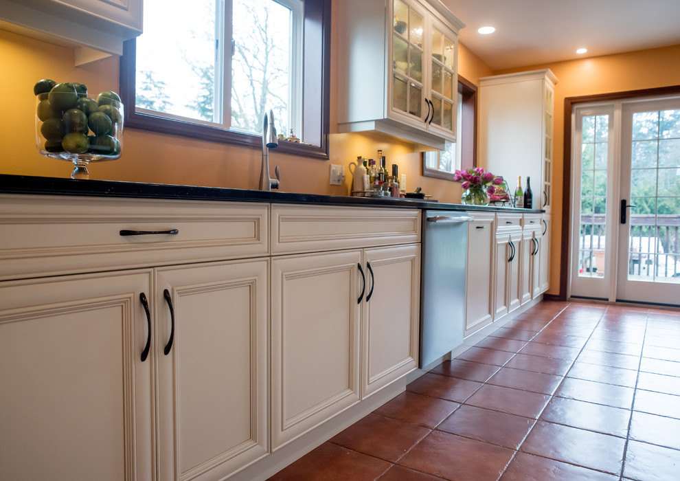 Klassische Küche mit Doppelwaschbecken, flächenbündigen Schrankfronten, weißen Schränken, Quarzit-Arbeitsplatte, Küchengeräten aus Edelstahl und Keramikboden in Vancouver