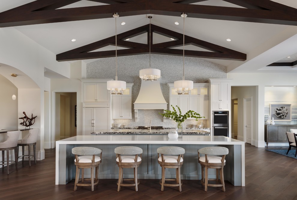 Klassische Wohnküche mit Küchenrückwand in Weiß, braunem Holzboden, zwei Kücheninseln und braunem Boden in Miami