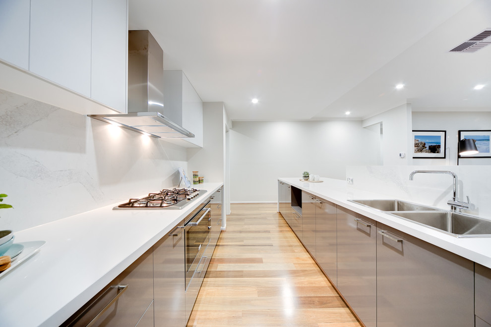 Contemporary l-shaped open plan kitchen in Perth with a double-bowl sink, flat-panel cabinets, grey cabinets, white splashback, stainless steel appliances, light hardwood flooring and an island.
