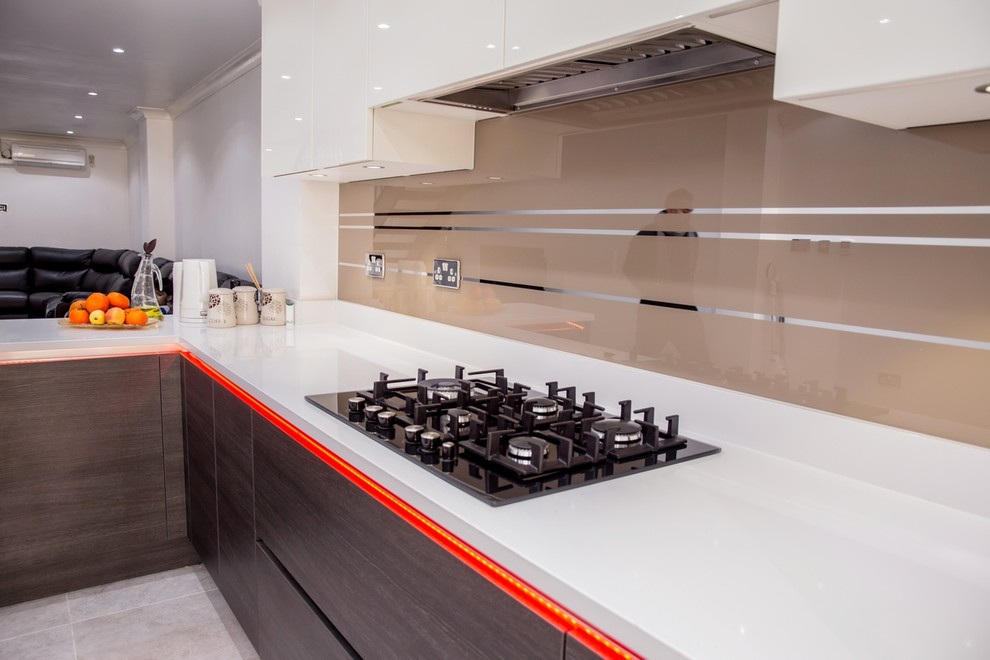 Modern kitchen in Hertfordshire with beige splashback and glass sheet splashback.
