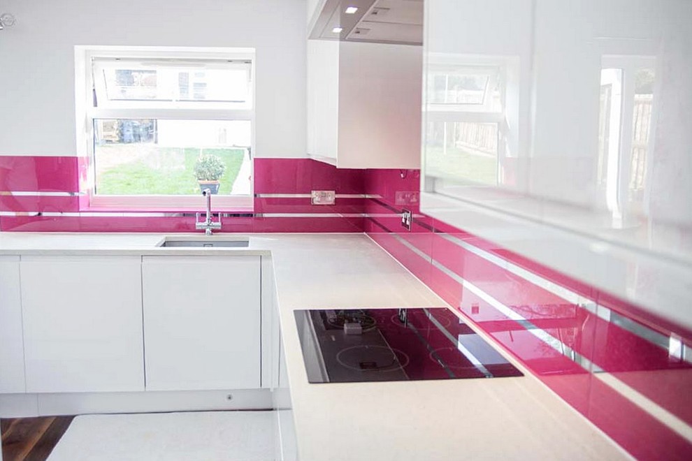 На фото: кухня в стиле модернизм с розовым фартуком и фартуком из стекла