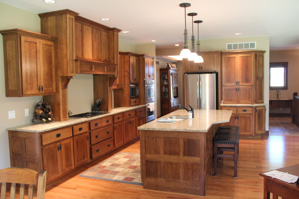 Immagine di una cucina con lavello sottopiano, top in granito, elettrodomestici in acciaio inossidabile e pavimento in legno massello medio