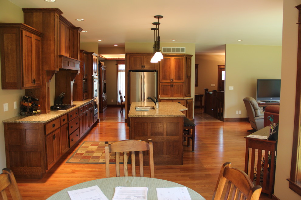 Küche mit Unterbauwaschbecken, Granit-Arbeitsplatte, Küchengeräten aus Edelstahl und braunem Holzboden in Chicago